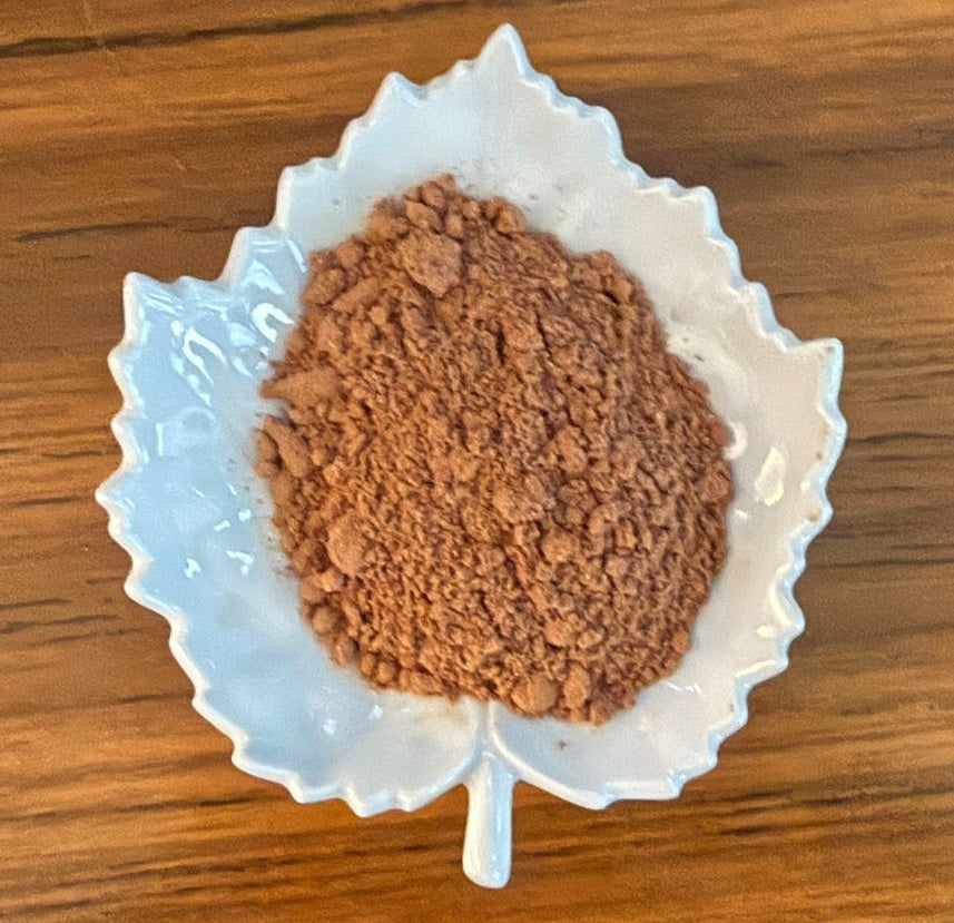 Adaptogen Hot Chocolate  powder in a white leaf-shaped container on a wooden surface