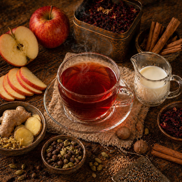 Apple Chai - Tea cup with steam, apples, spices, and milk on a wooden surface