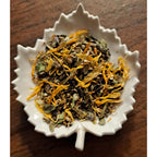 Calming Linden herbal blend on a white leaf shaped ceramic dish on a wooden surface