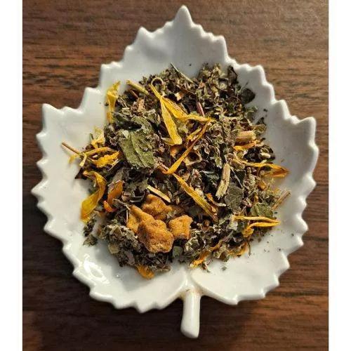 Herbal blend of Country Comfort herbal tea in a white leaf-shaped bowl on a wooden surface