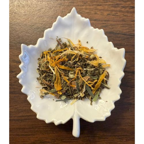 Healthy Liver herbal blend on a white leaf shaped ceramic dish on a wooden surface