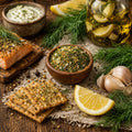 Lemony Dill Mic in a bowl, with a Salmon dish, Lemony dill infused oil, and herbs, lemon, and crackers on a wooden surface