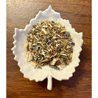 Migraine Relief herbal blend on a white leaf shaped ceramic dish on a wooden surface