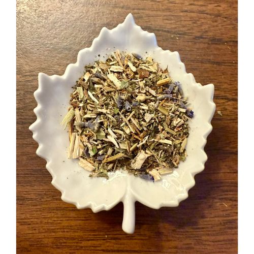 Migraine Relief herbal blend on a white leaf shaped ceramic dish on a wooden surface
