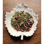 Mom's Morning Wellness herbal blend on a white leaf shaped ceramic dish on a wooden surface
