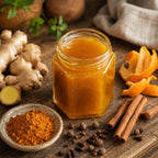 Jar of Raw Mulling Spice Honey with ginger, orange peels, cinnamon sticks, and other spices on a wooden surface.
