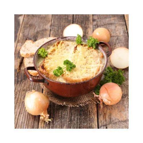 Baked dish in a brown pot on a wooden surface with onions and bread.