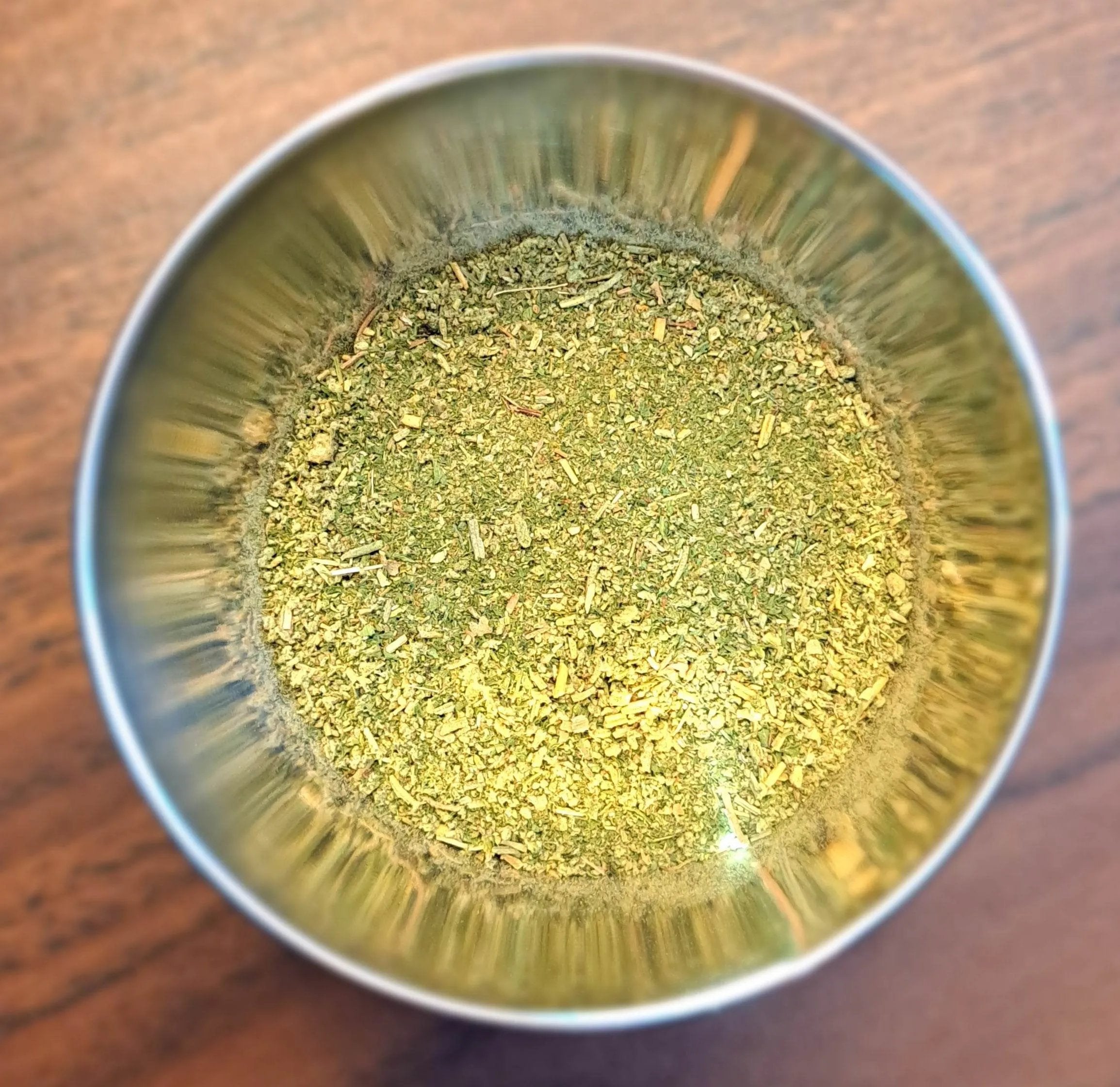 Metallic bowl with Poultry Seasoning on a wooden surface