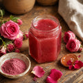Jar of Rose Honey  on a wooden surface with pink roses and a bowl of pink powder.