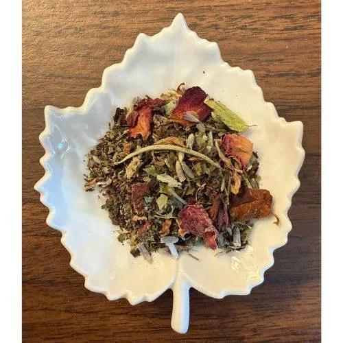 Serenity Haven tea mix in a white leaf-shaped bowl on a wooden surface