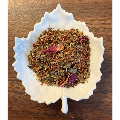 Simple Pleasures herbal blend on a white leaf shaped ceramic dish on a wooden surface