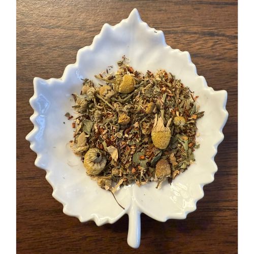 Sip & Sooth herbal blend on a white leaf shaped ceramic dish on a wooden surface