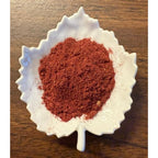 Spiced RUby Latte herbal blend on a white leaf shaped ceramic dish on a wooden surface