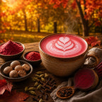 Steaming red latte with heart design, surrounded by autumn ingredients and leaves.
