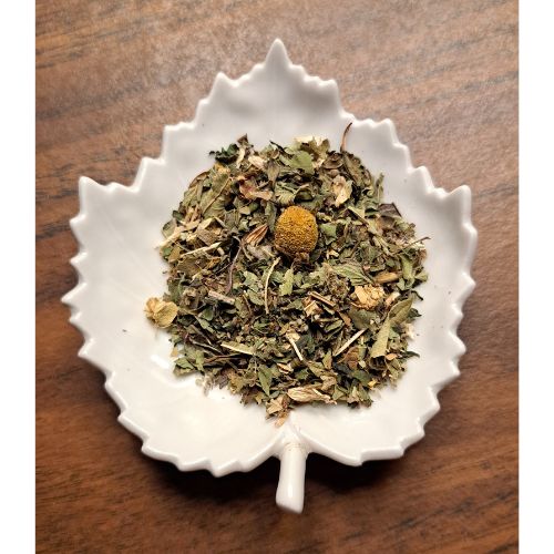 Stress Ease herbal blend on a white leaf shaped ceramic dish on a wooden surface