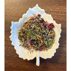 Teacher Fuel herbal blend on a white leaf shaped ceramic dish on a wooden surface