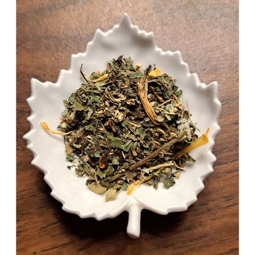 Tend & Mend Herbal Teablend on a white leaf-shaped ceramic dish on a wooden surface