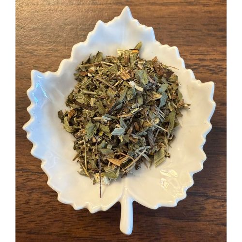 UTI herbal blend on a white leaf shaped ceramic dish on a wooden surface