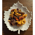 
Winter Punch Tea herbal blend on a white leaf shaped ceramic dish on a wooden surface