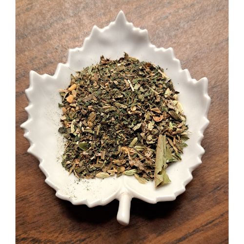 Woman's Tea Tonic herbal blend on a white leaf shaped ceramic dish on a wooden surface